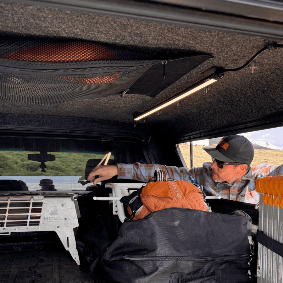 Man reaching into a truck cap lit by a Kingpin light on the ceiling