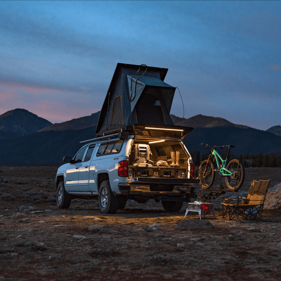 Truck with a rooftop tent at dusk, tailgate and camp lit by Kingpin lights