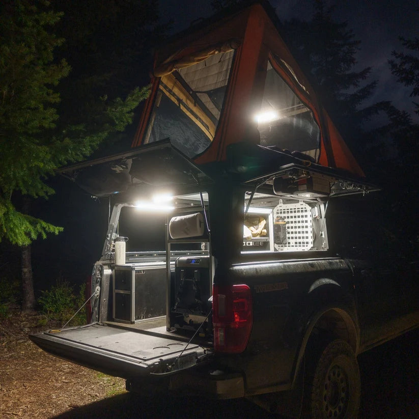 Truck with a rooftop tent at night, camp kitchen lit by Kingpin lights