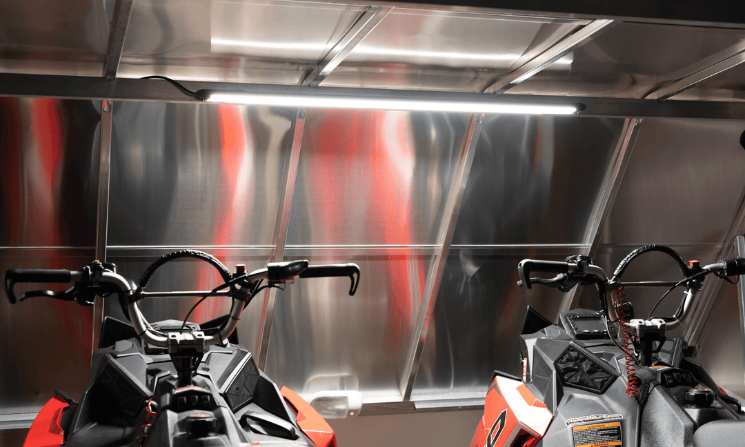 Kingpin v-Series 40" light bar illuminating two Polaris mountain snowmobiles inside enclosed aluminum trailer.