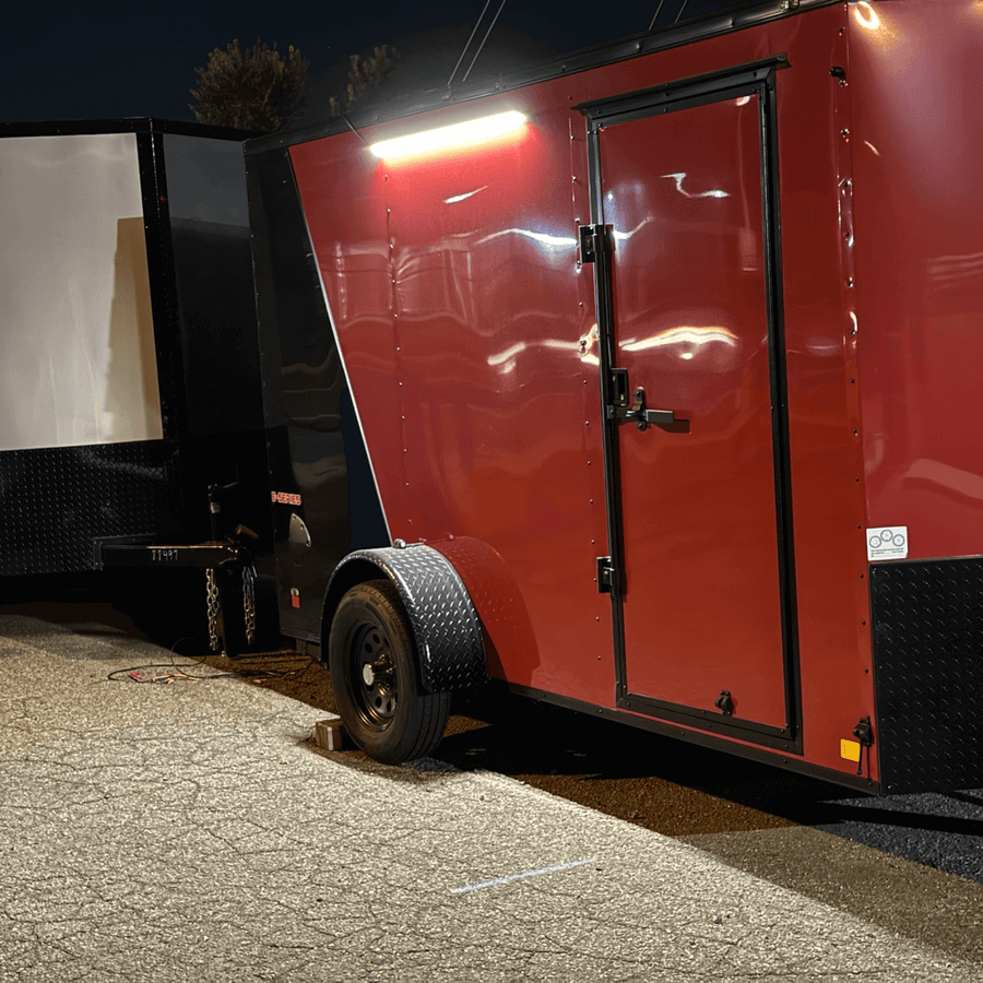 Red enclosed trailer at night with a Kingpin light over the side door