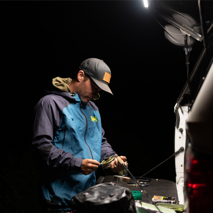 Man working at a truck tailgate at night under a Kingpin light
