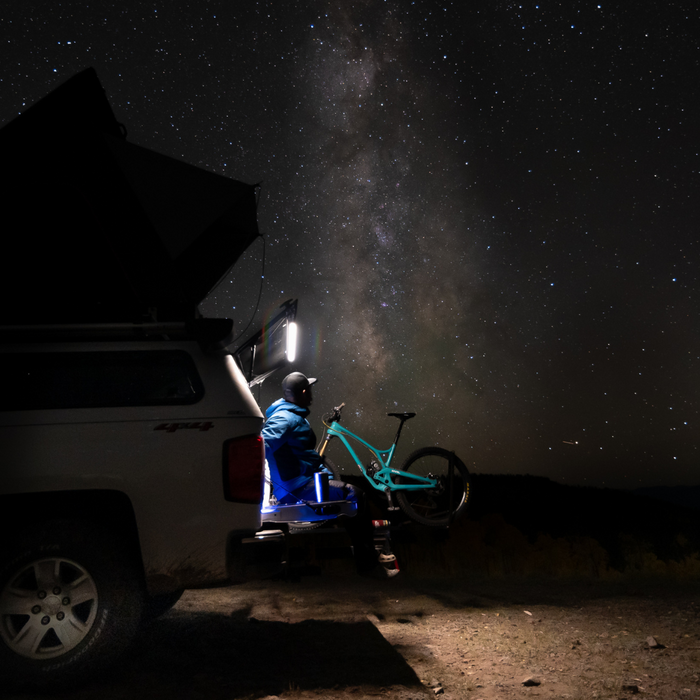 Person with a bike next to a truck at night under the stars, lit by a Kingpin light
