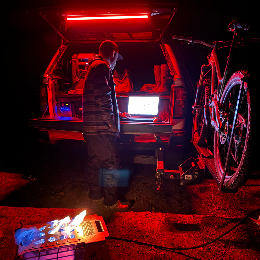 SUV hatch lit red by a Kingpin F-Series light at a night camp