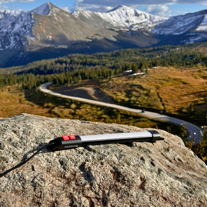 Kingpin F-Series light on a rock with mountains and a winding road behind it