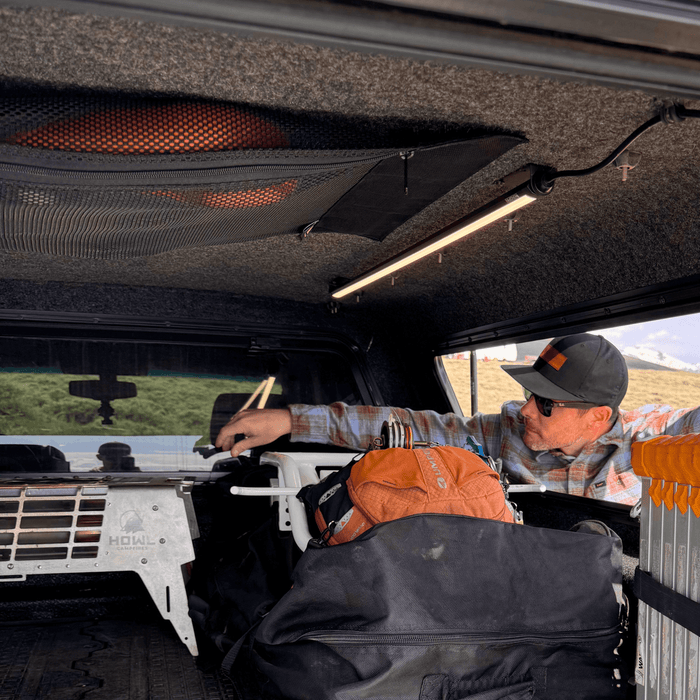 Man reaching into a truck cap lit by a Kingpin light on the ceiling