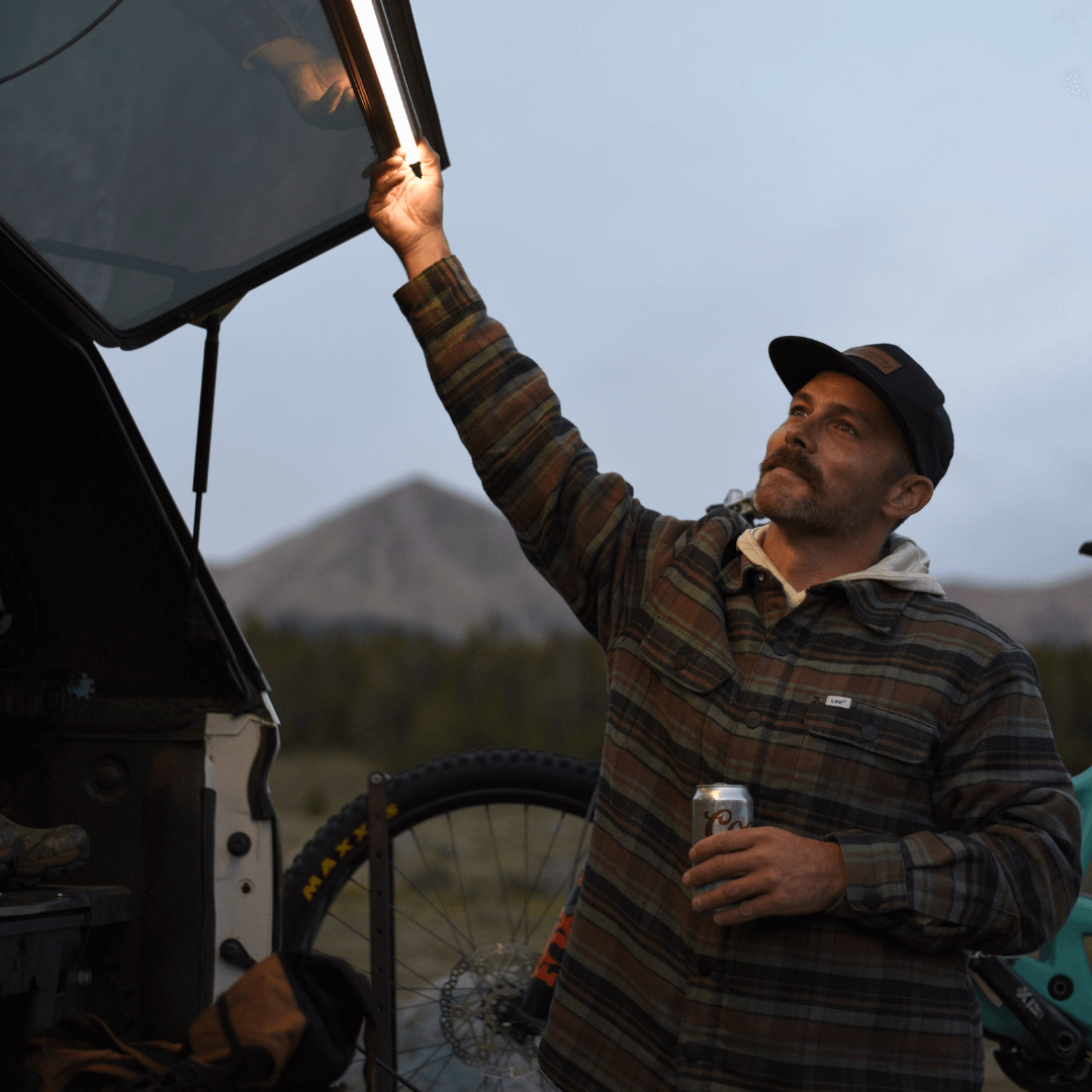 Man aiming a Kingpin light mounted on the tailgate door of a truck cap