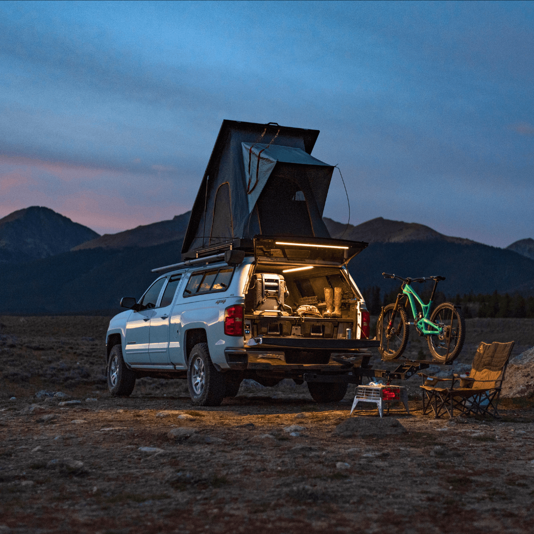 Truck with a rooftop tent at dusk, tailgate and camp lit by Kingpin lights