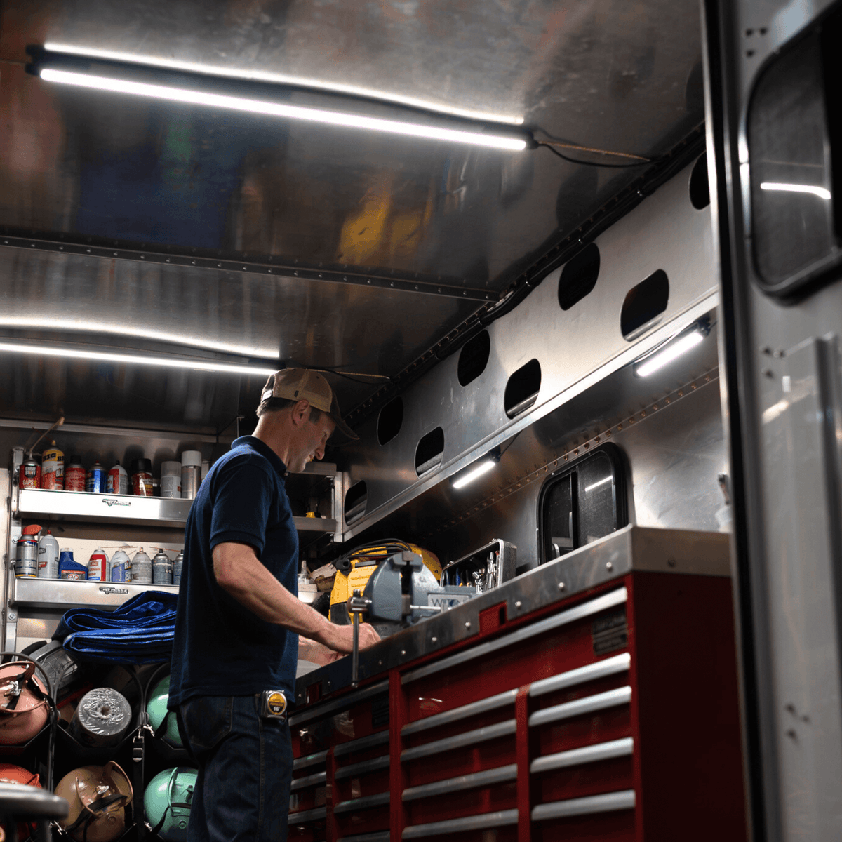 Man at a tool bench inside a work truck body lit by Kingpin lights