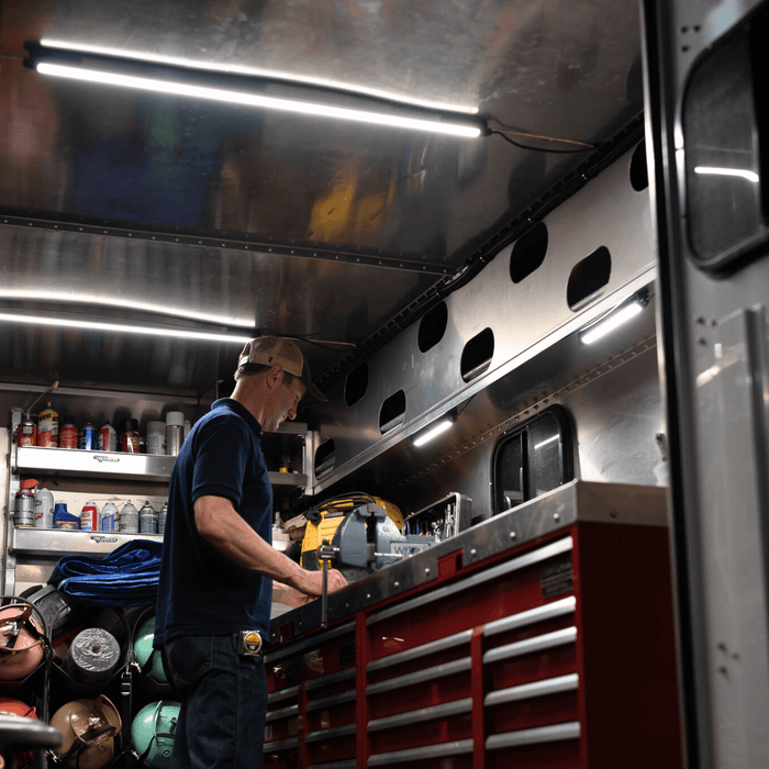 Man at a tool bench inside a work truck body lit by Kingpin lights