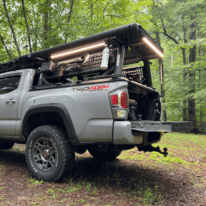 Pickup with a bed rack and Kingpin lights in a forest campsite