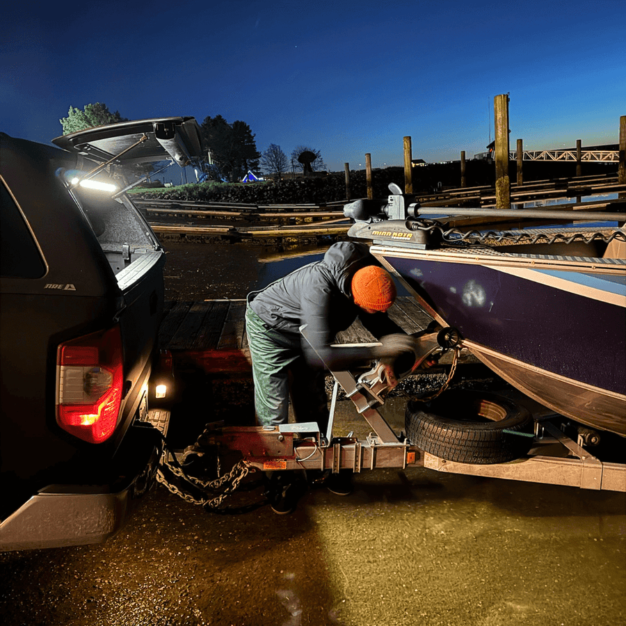 Man hitching a boat trailer at night beside a truck lit by a Kingpin light