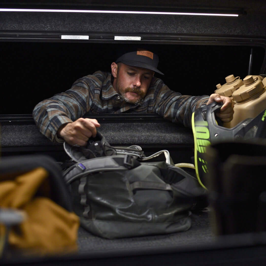 man reaching inside truck bed cover lights on at night
