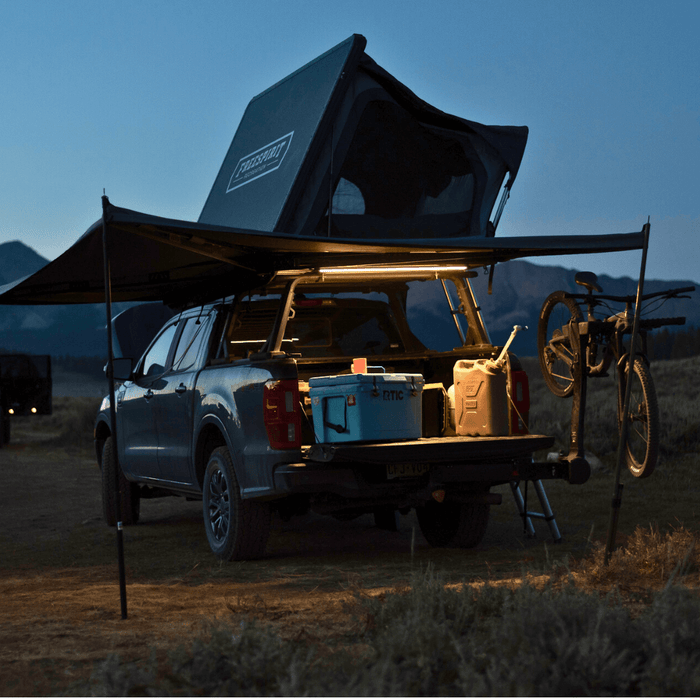 Truck with a rooftop tent and awning at dusk, bed lit by Kingpin lights