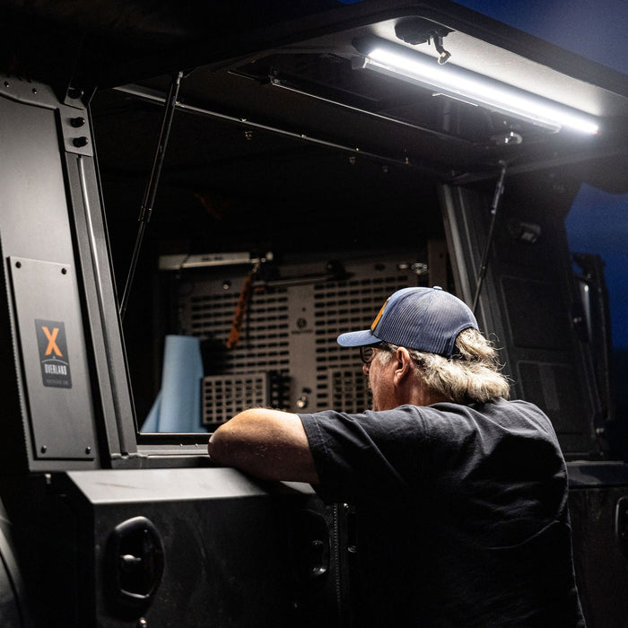 Man leaning into a truck camper lit white by a Kingpin F-Series light