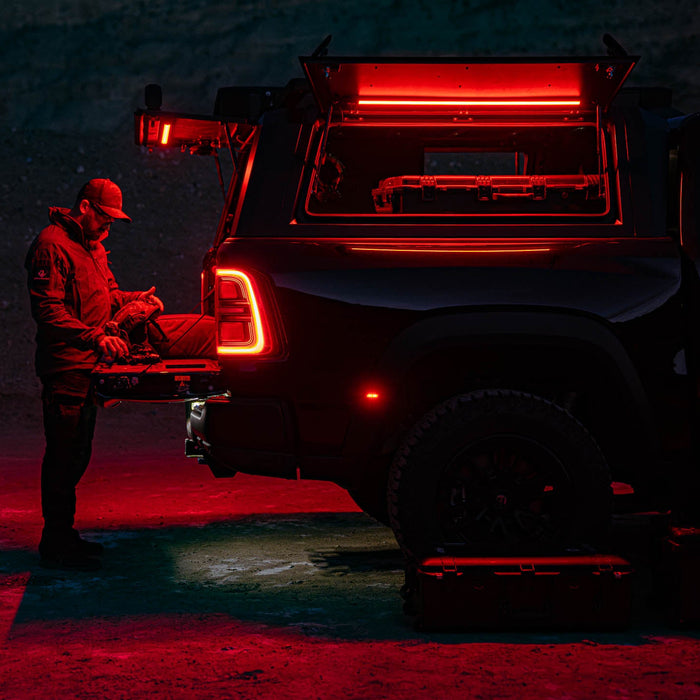 Man at an SUV tailgate at night lit by a Kingpin F-Series light in red mode