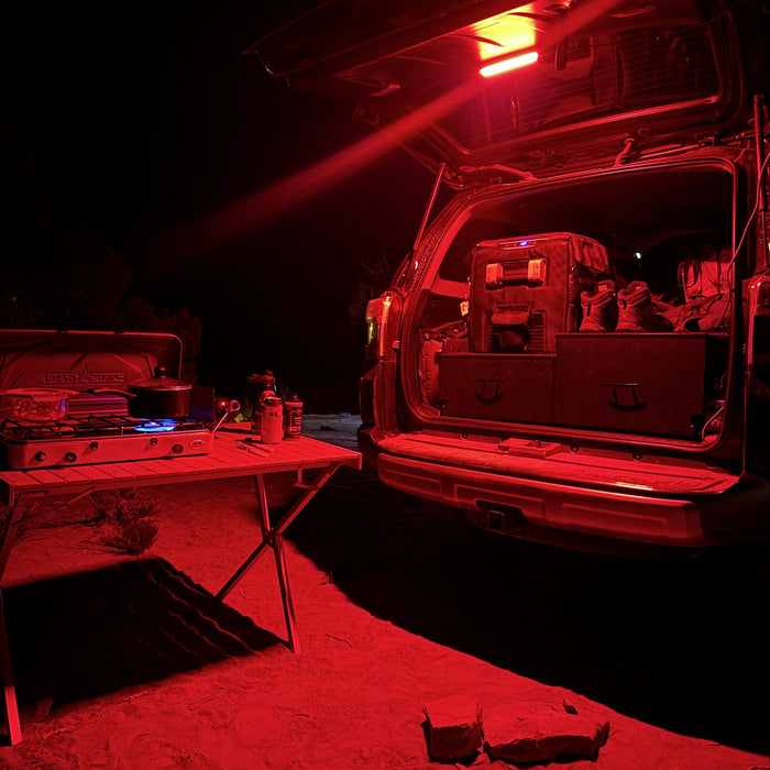 SUV hatch and camp table lit red at night by a Kingpin F-Series light