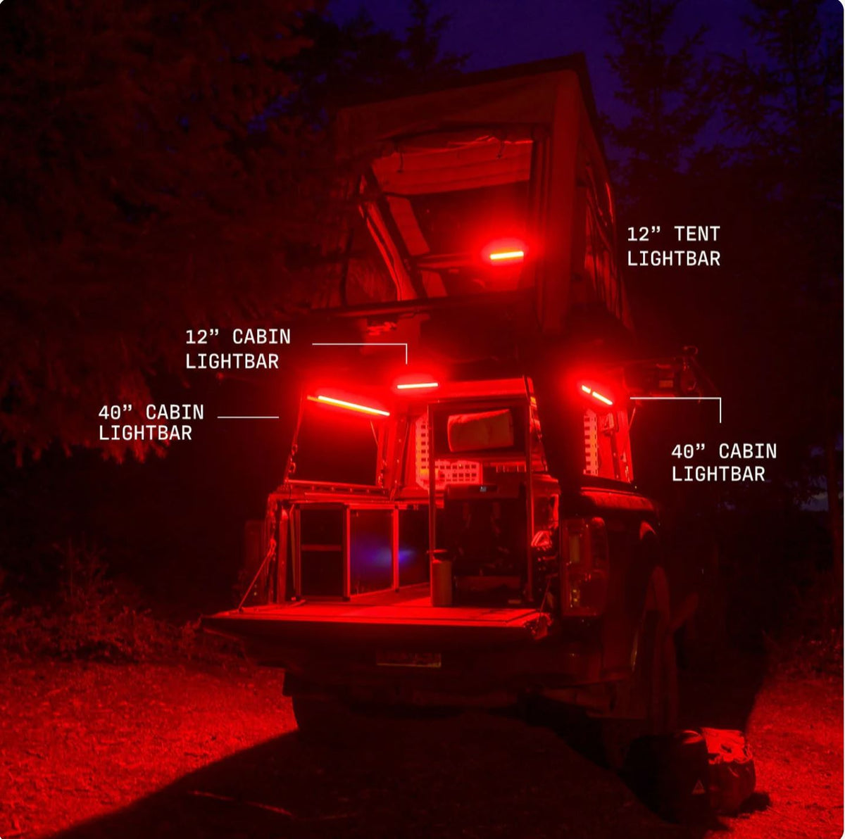 Truck camper at night lit red by Kingpin F-Series lights in the cabin and tent
